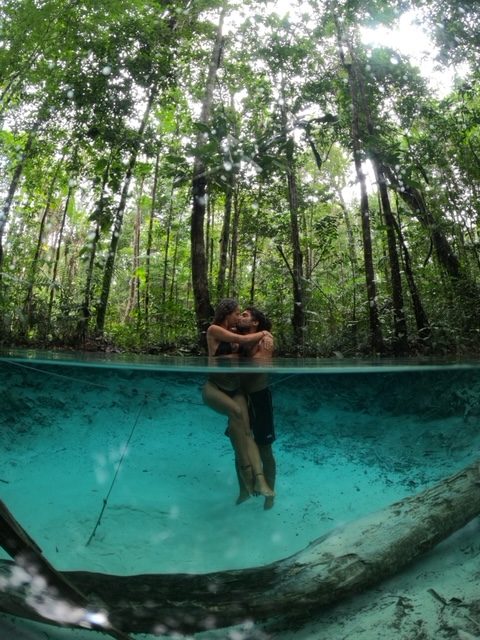 Homem e mulher se beijando em uma lagoa com água azul.