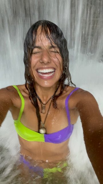 Mulher tomando banho dentro de uma cachoeira em Presidente Figueiredo.