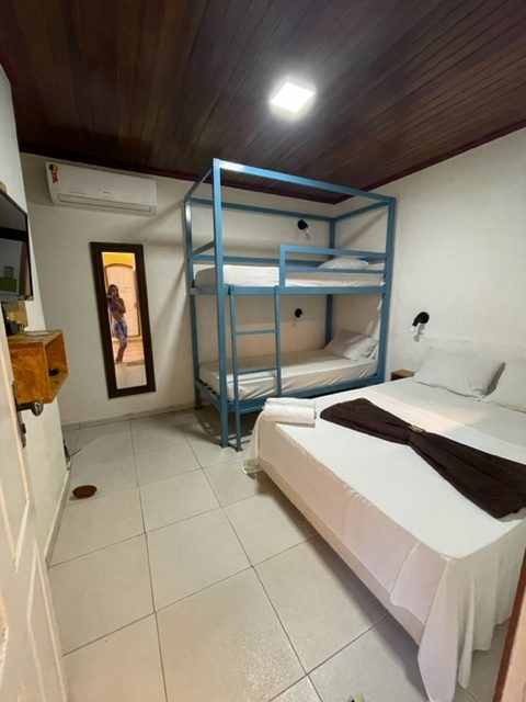 Quarto com uma cama de casal e um beliche, televisão e ar condicionado