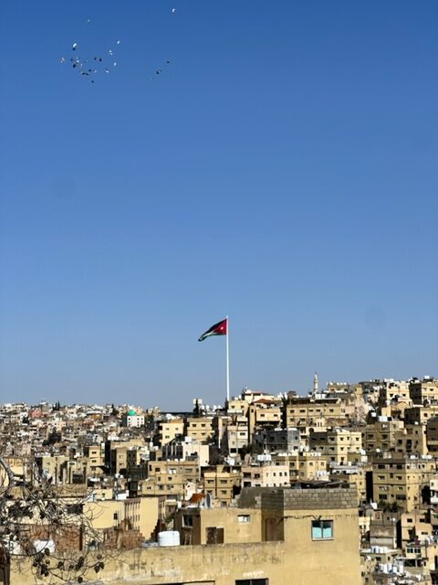 Panorama da cidade de Amã e bandeira da Jordânia