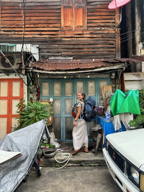 Mulher com mochilas em frente a uma casa em Bangkok