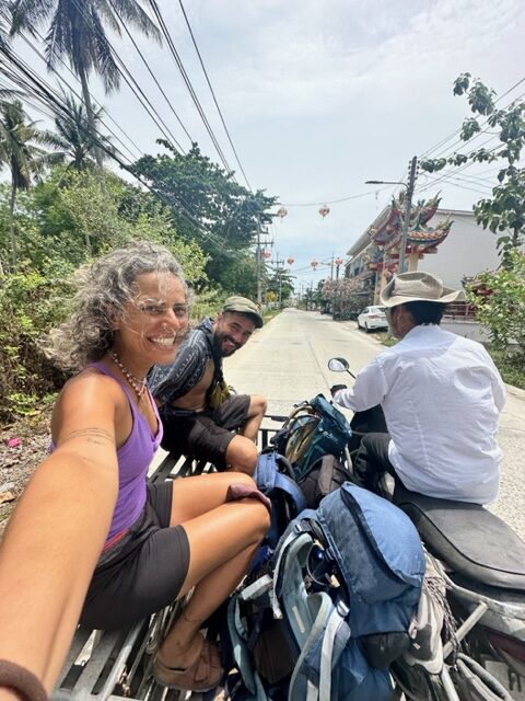 Mulher e dois homens em uma moto com carroça e com mochilas