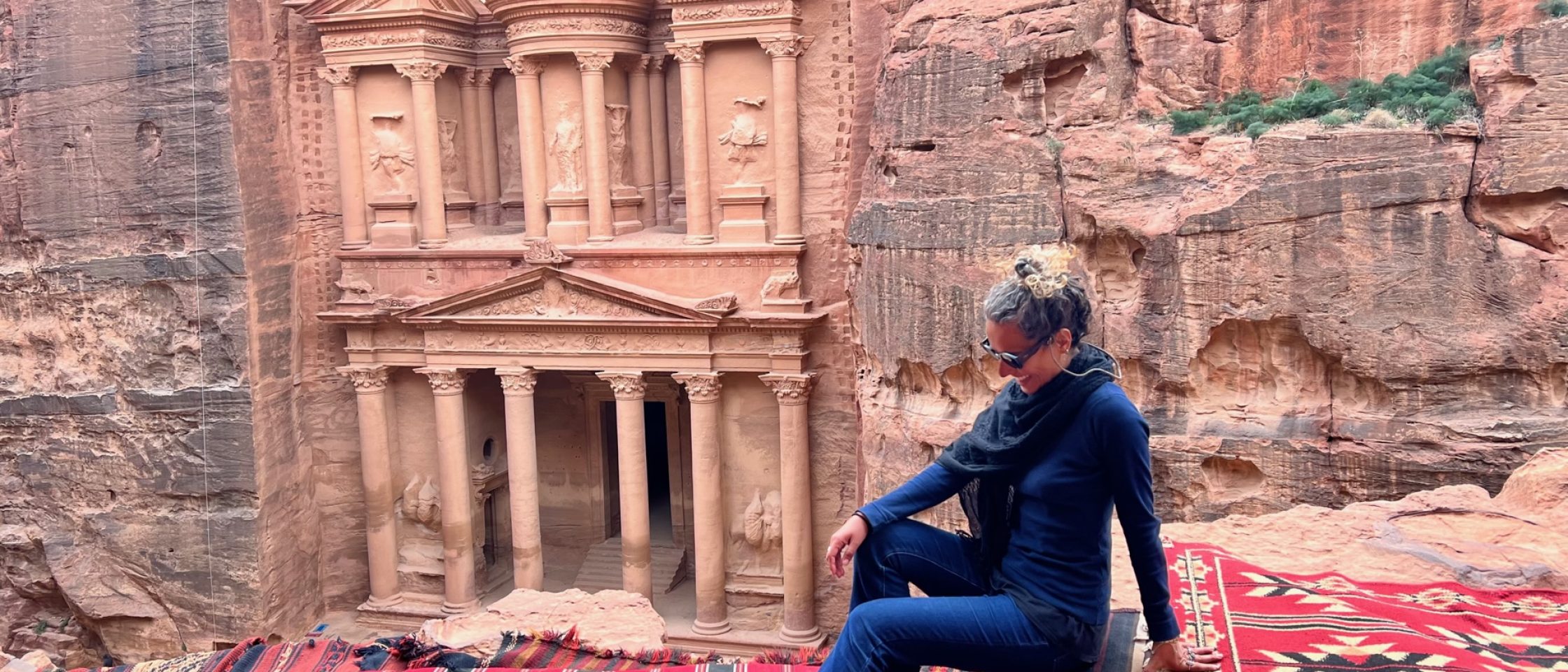 mulher sentada na frente de um monumento em Petra, em um roteiro pela Jordânia