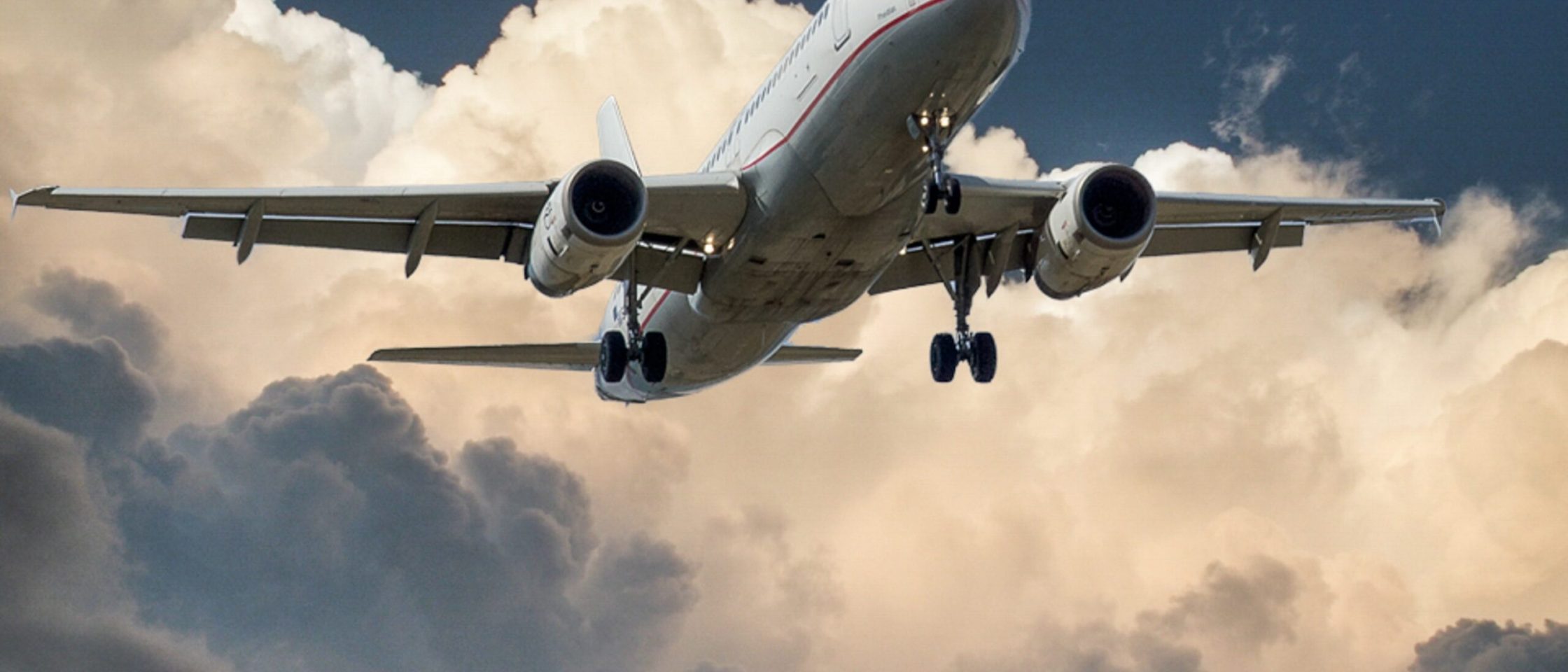 Um avião voando e o céu com nuvens no fundo